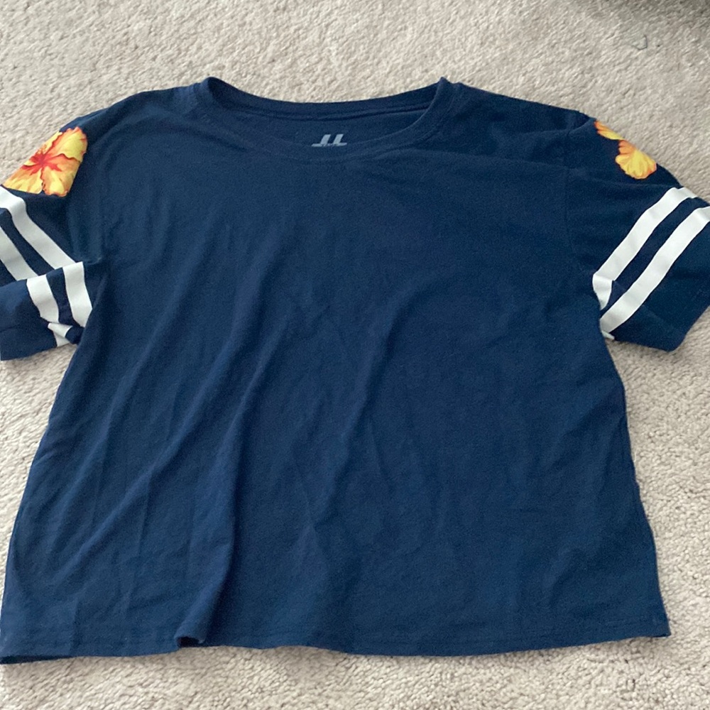 Cropped navy top with an orange flower and two white stripes on each sleeve